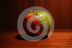 Green and red apple stapled with two halves