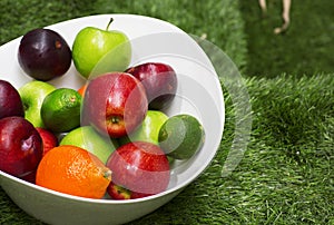 Green and red apples in a big white dish.