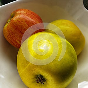 Green and red apples in a white dish