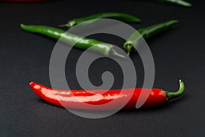 Green and red chili peppers on black background. Hot spicy food.