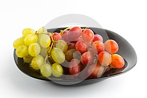 Green and red grapes put in a black platter isolated on an empty white background