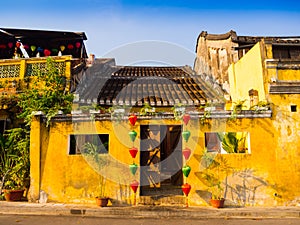 Green and red lanterns hanging outside of an old yellow house in Hoi An ancient town, UNESCO world heritage. Hoi An is