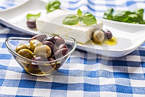 Green and red olives in bowl with olive oil and greek feta cheese in the background