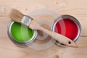 Green and red paint in the bank to repair and brush on the light wooden background