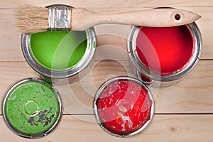 Green and red paint in the bank to repair and brush on the light wooden background