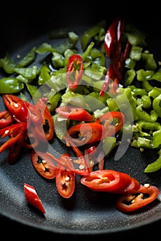 Green and red peppers for fajita in a frying pan closeup