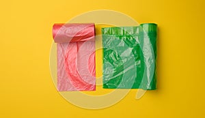 Green and red plastic bags for trash can on yellow background