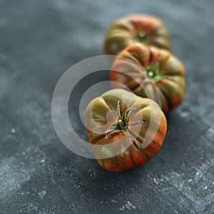 Green and red tomatoes on black background. Healthy food. Shallow depth of field