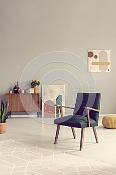 Green retro armchair in grey living room interior with wooden furniture