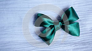 Green ribbon bow on white fabric background