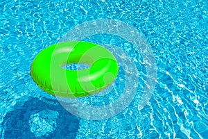 Green ring floating in blue swimming pool. Inflatable ring, rest concept