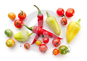 Green and ripe cherry tomatoes, bell peppers, chili on white