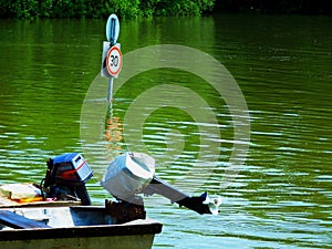 Green river flooding with submerged road sign and small motor boat