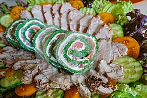 Green roll with fish. A plate with greens and salad and cold cuts