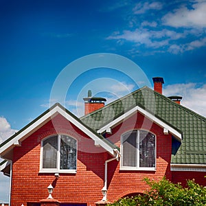 The green roof of the beautiful house with nice window and blue