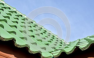 Green roof tile pattern over blue sky