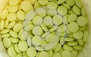 Green round tablets in white jar in medical healthcare drugstore concept,closed up