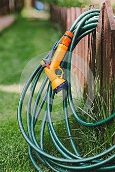 A green rubber garden hose with nozzle