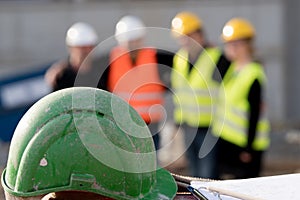 Verde casco sul primo piano. gruppo da quattro costruzione lavoratori in posa sul fuori da focalizzata 