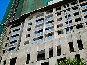 Green safety nets netting mesh surrounding whole high rise apartment condo tower under construction, prevents dropping of building