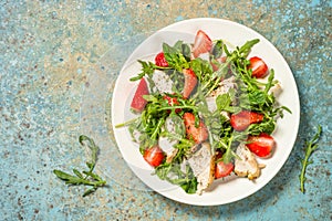 Green salad with chicken, strawberry and arugula.