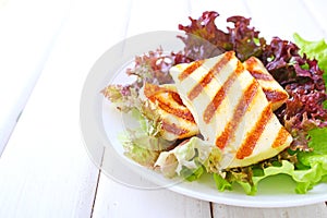 Green salad with fried halloumi cheese in a white plate