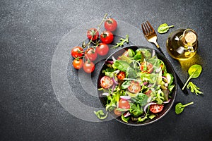 Green Salad with salad leaves and vegetables at black background.