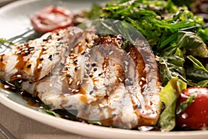 Green salad with smoked eel fish, avocado slices and chuka seaweed, close-up. Japanese cuisine concept.