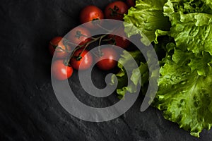 Green salad and tomatoes twig one the black stone table