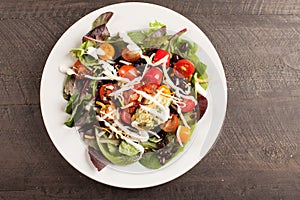 Green salad topped with beans, tomato and cheese on a plate horizontal shot