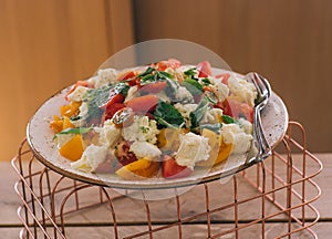 Green salad with vegetables on the metalic net and wooden table