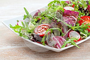 Green salat in a bowl on desk. Tomato, cheese and salad.