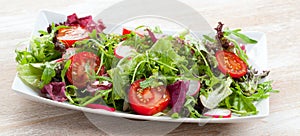 Green salat in a bowl on desk. Tomato, cheese and salad.