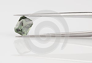 Green Sapphire Held in Gemstone Tweezers photo