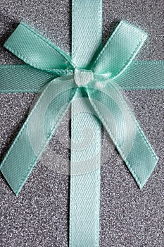 Green satin ribbon bow on a gray background.