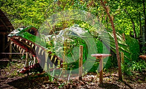 Green scaly dragon in woody park where children can play inside