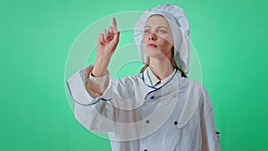 Green screen concept baker woman in a uniform very concentrated and enthusiastic typing something with a finger virtual