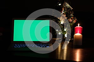 Green screen laptop computer and christmas tree and candle light