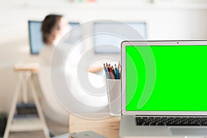 Green screen laptop computer and a glass with color pencils