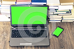 Green screen laptop, stack of books, smartphone, notebook and pencils on white table, education office concept background