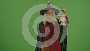 Green Screen. A Portrait of an Old Wizard Walks With a Lamp in His Hand.