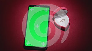 Green screen smartphone with chroma key for Valentine's day. Red background defocused lights hearts