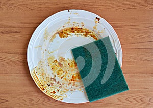 Green scrub sponge purely to food stain on white dish photo