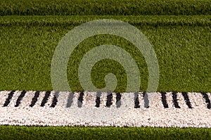 Green sculpture of grand piano with real white and black keyboard made from artificial grass.