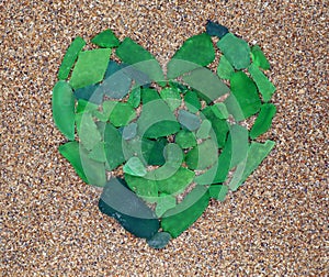 Green sea glass heart symbol on the sand. Beach mediteranian sea. Spain. Vacation. photo