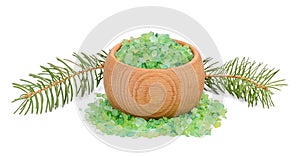 Green sea salt for bathing in wooden bowl and fir branches behind