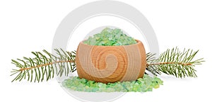 Green sea salt for bathing in wooden bowl and spruce branches behind