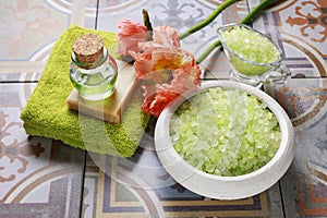 Green sea salt, soft towel, bottle of essential oil, bar of soap and poppy flower