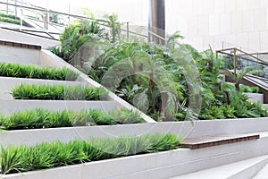 Green seating area indoors, an empty bench to rest among plants and foliage in a public place. Modern architecture.