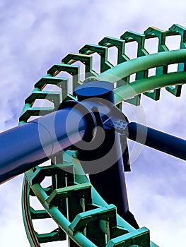 green section of a roller coaster track coming out of a loop with blue support beam